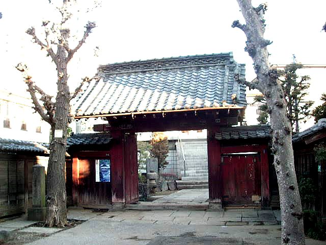 根生院の山門（赤門）を正面から見る。二本の欅の間に朱塗りの門が立つ