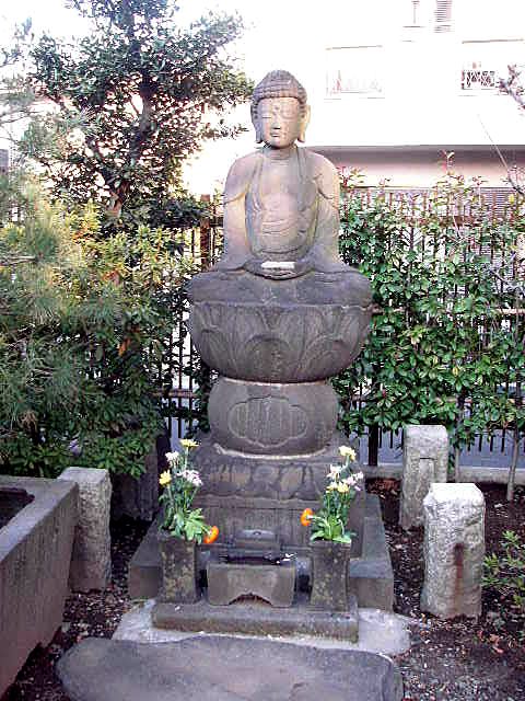 石造の大日如来坐像。蓮華座と二重の台座の上に安置され、花が供えられている