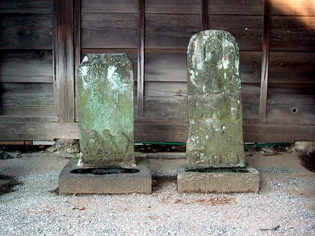 二基の庚申塔。板壁の前に並んで安置され、右の一基には像が浮彫されている